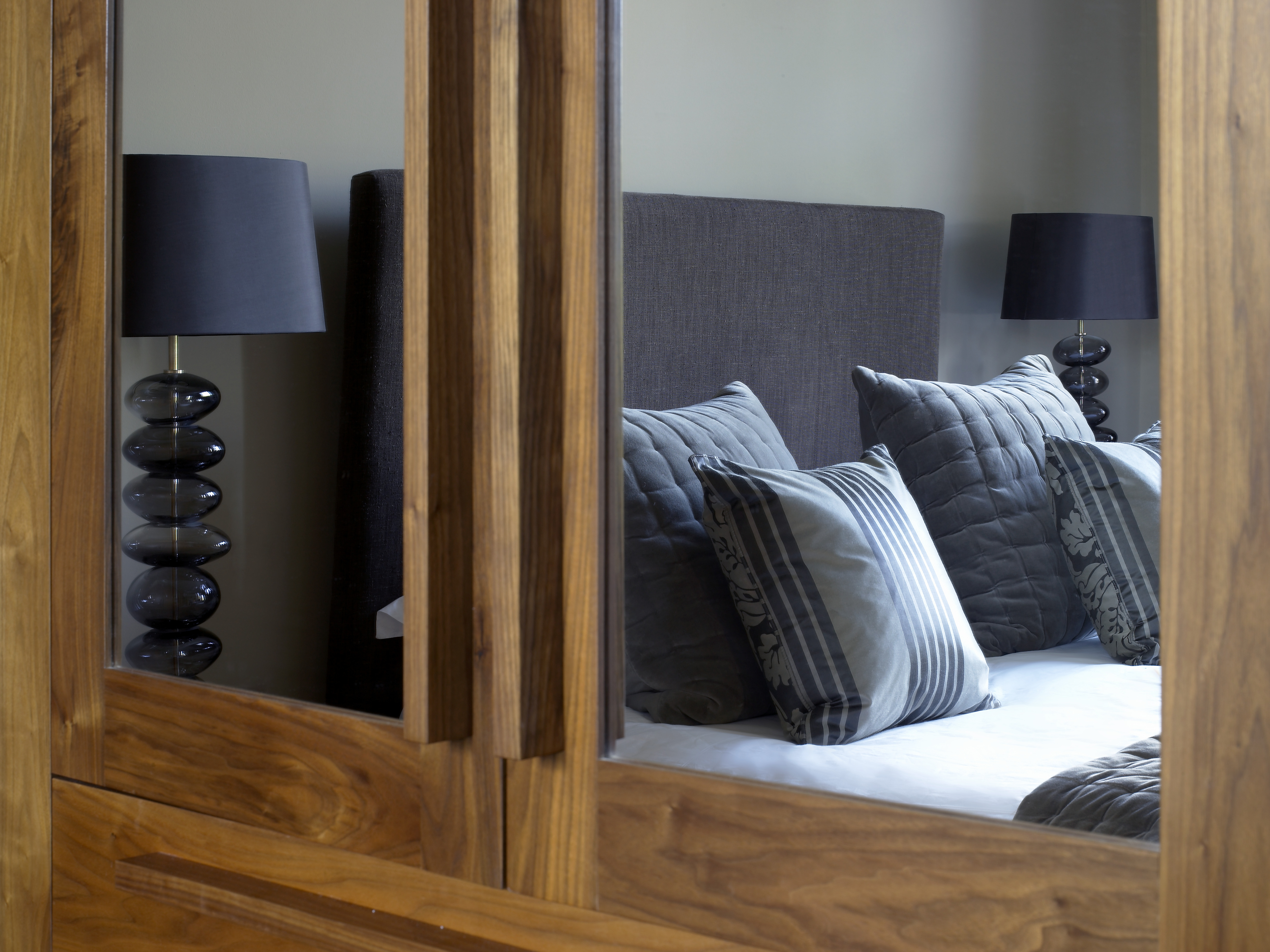 Master bedroom with smoked glass pebble bedside lamps and bespoke walnut wardrobes.