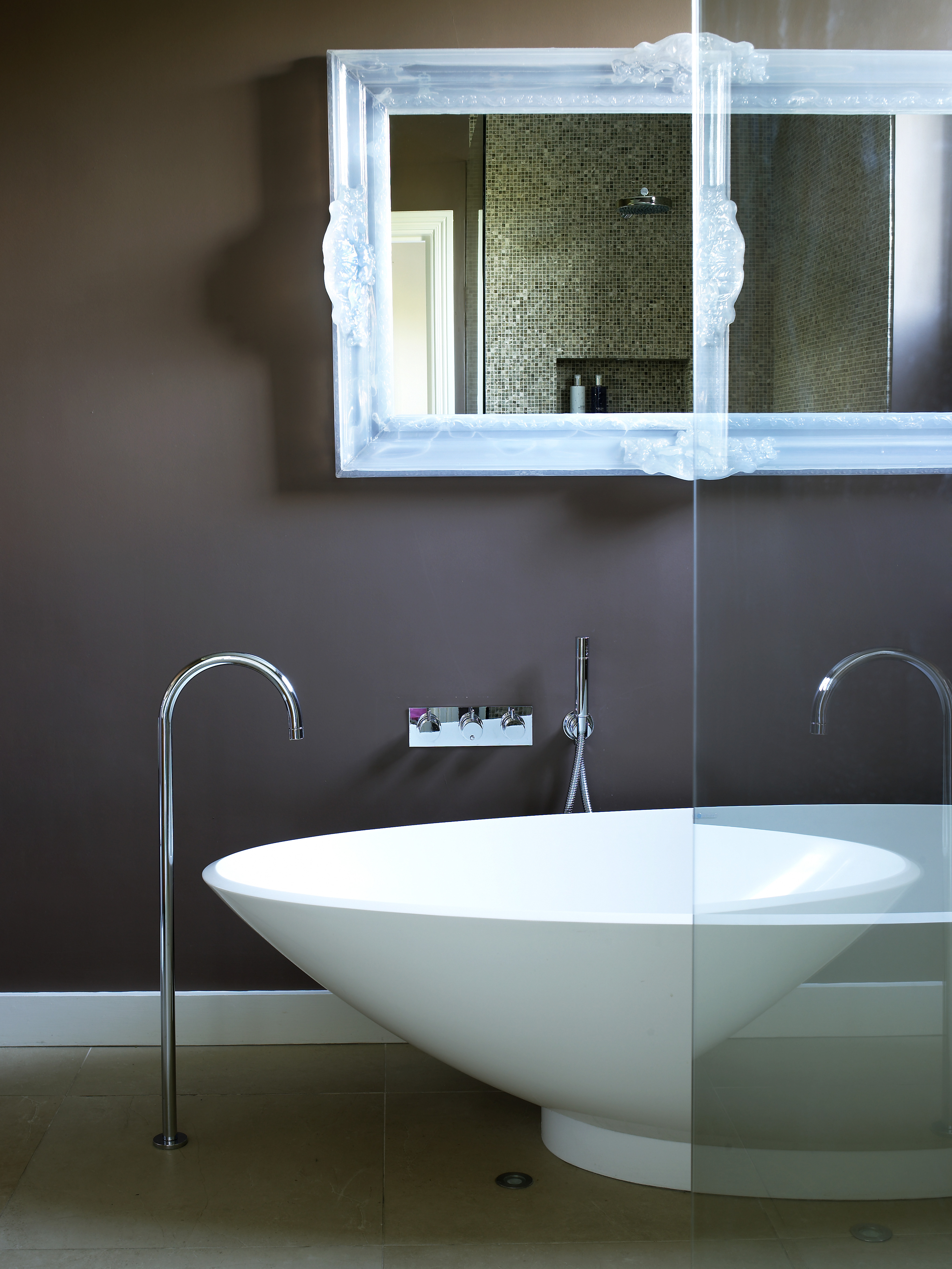 Freestanding bath with chrome floor spout and wall mounted controls in contemporary bathroom.