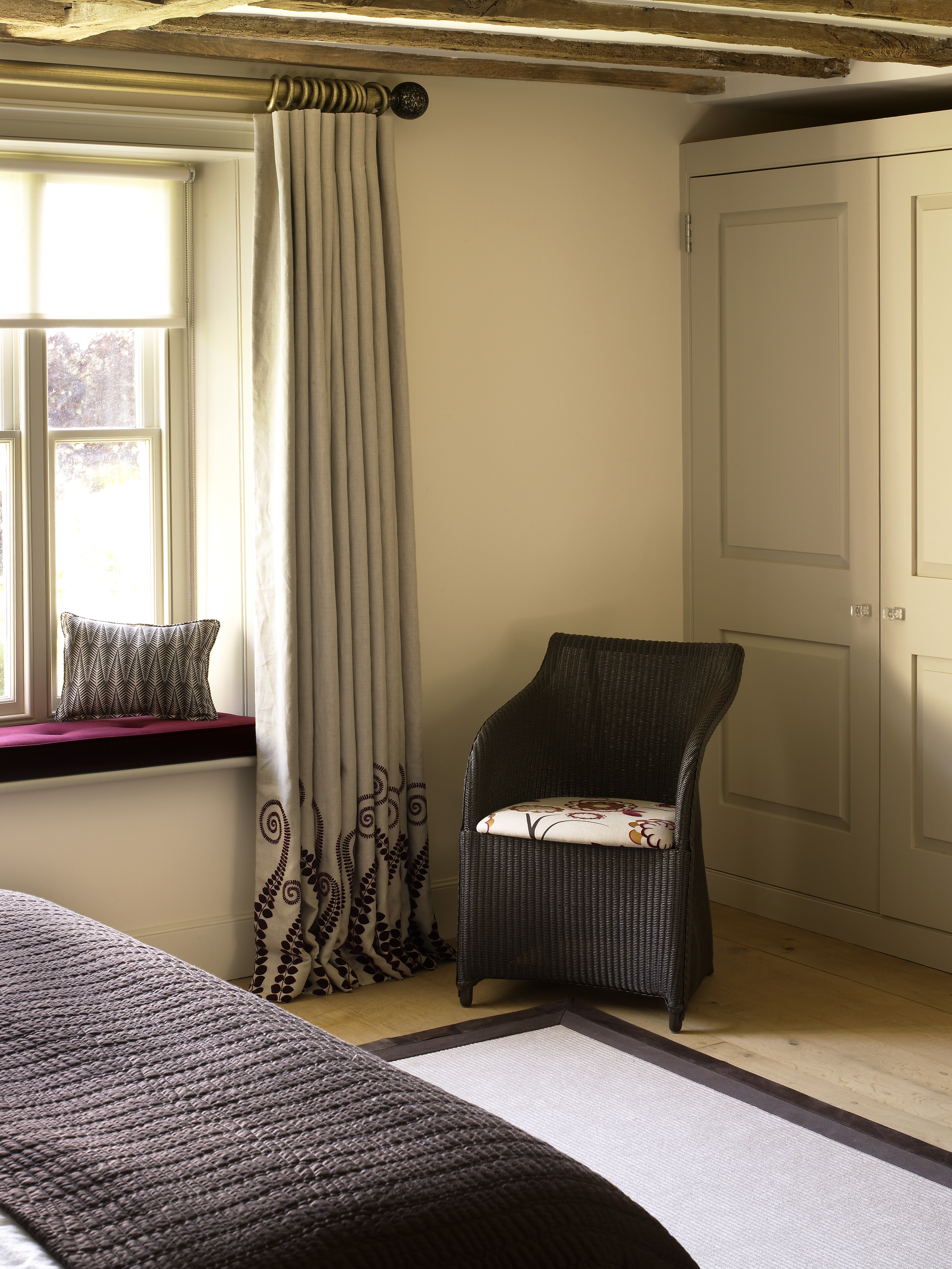 Armchair and cushions to the front of classic styled console and bronzed sculpted table lamp by Porta Romana.