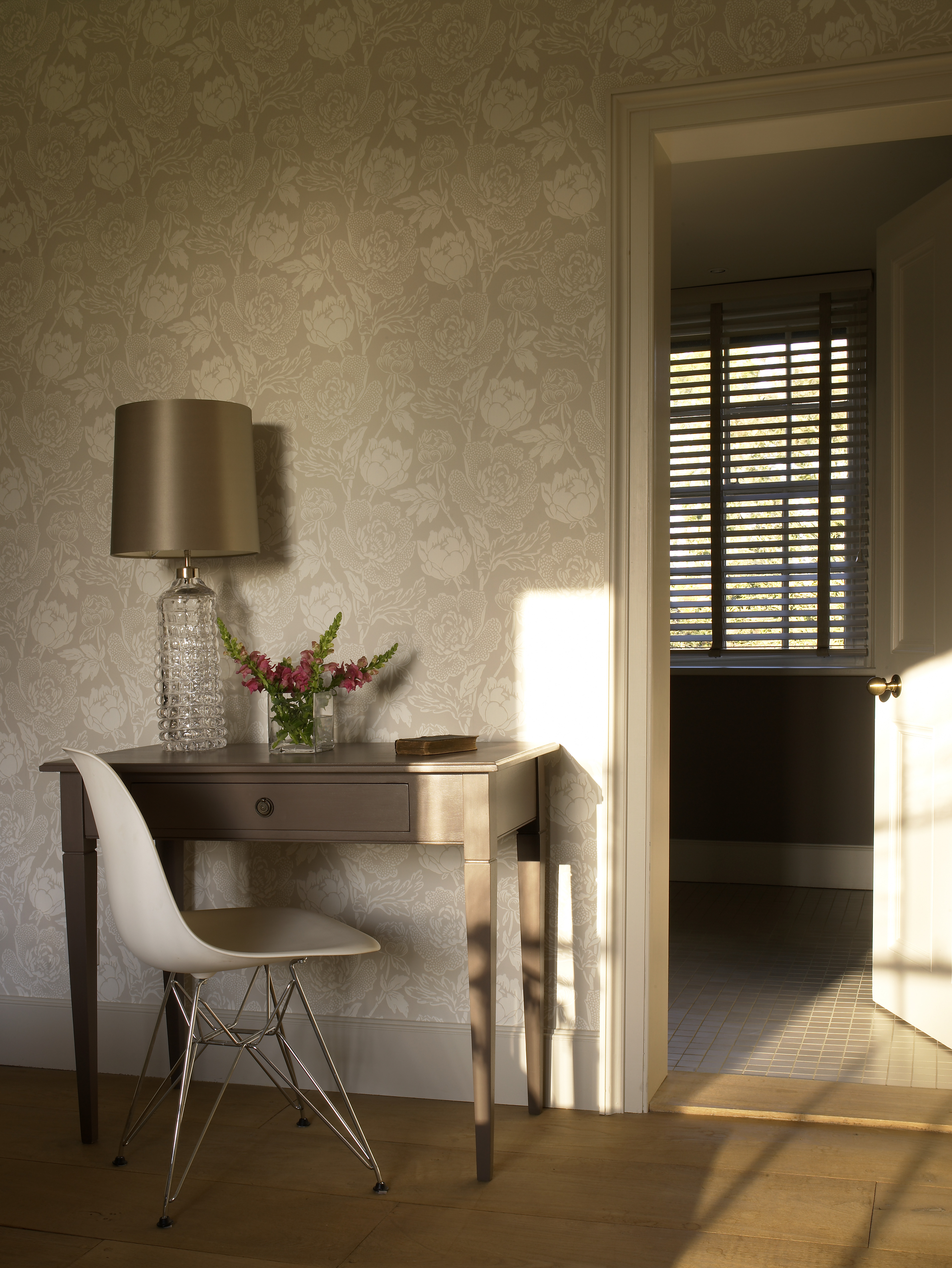 Armchair and cushions to the front of classic styled console and bronzed sculpted table lamp by Porta Romana.