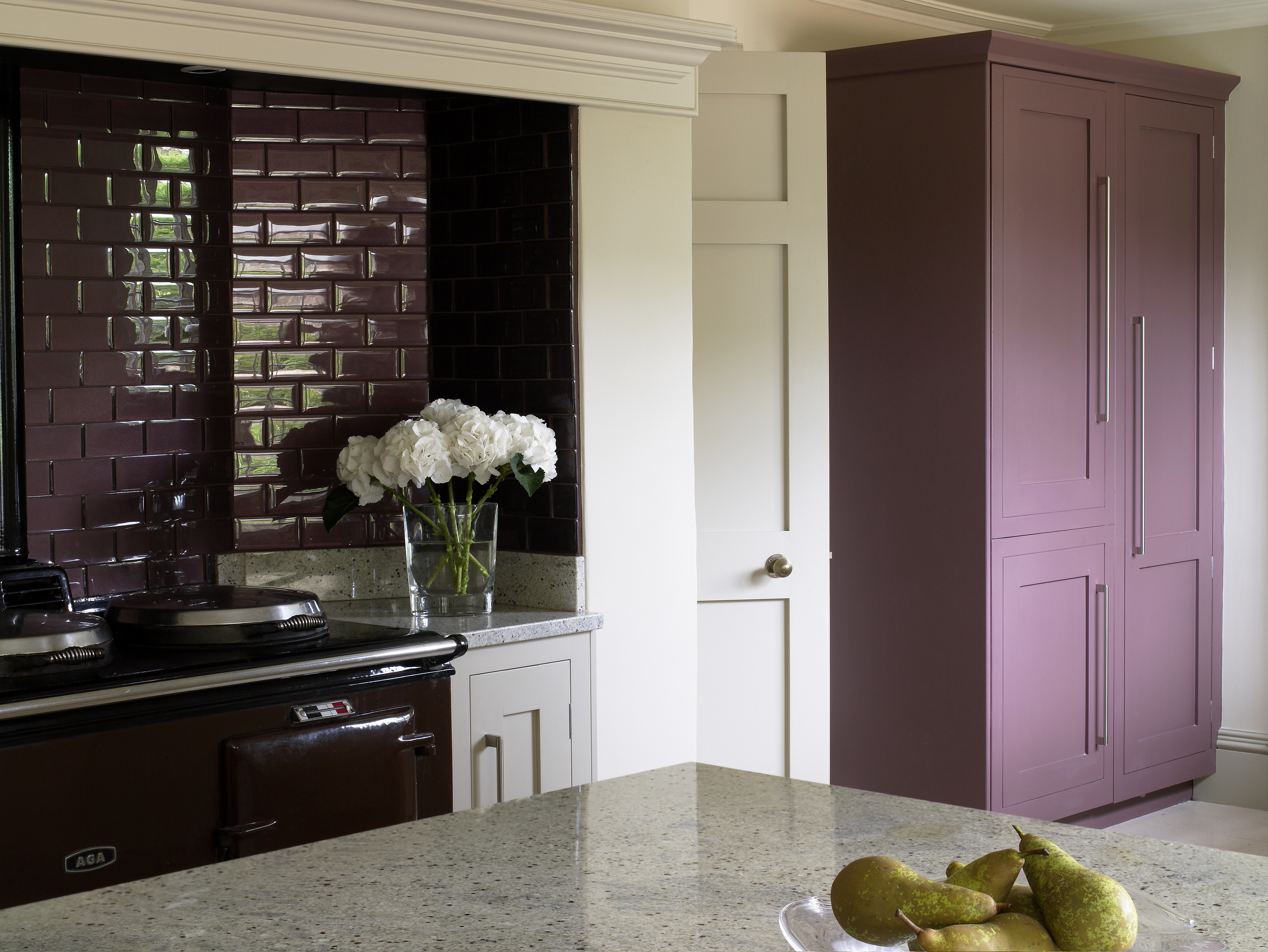 Contemporary design of country kitchen showing Aga and metro tile surround and painted plum coloured cabinet.
